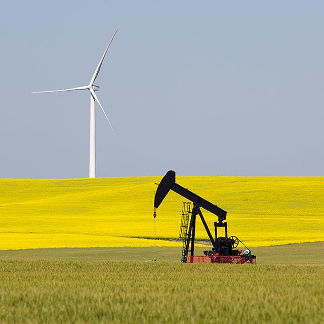 An open field is home to both a pumpjack and a wind turbine